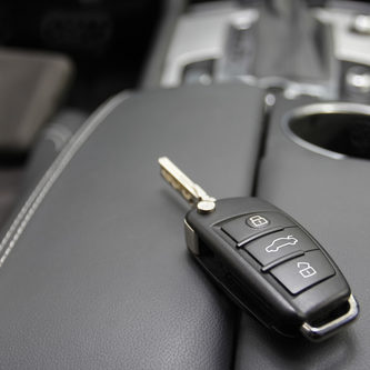 car key to a German luxury car, the key is lying on dark leather.